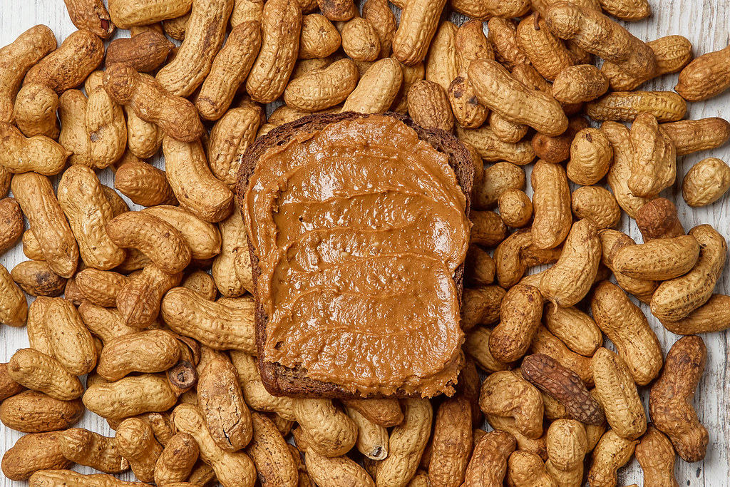 Peanut butter sandwich on pile of whole nuts