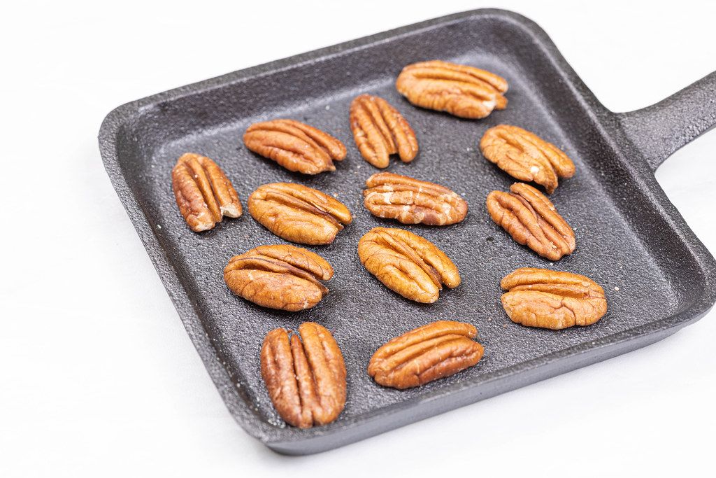 Pecan Nuts on the black steel pan above white background