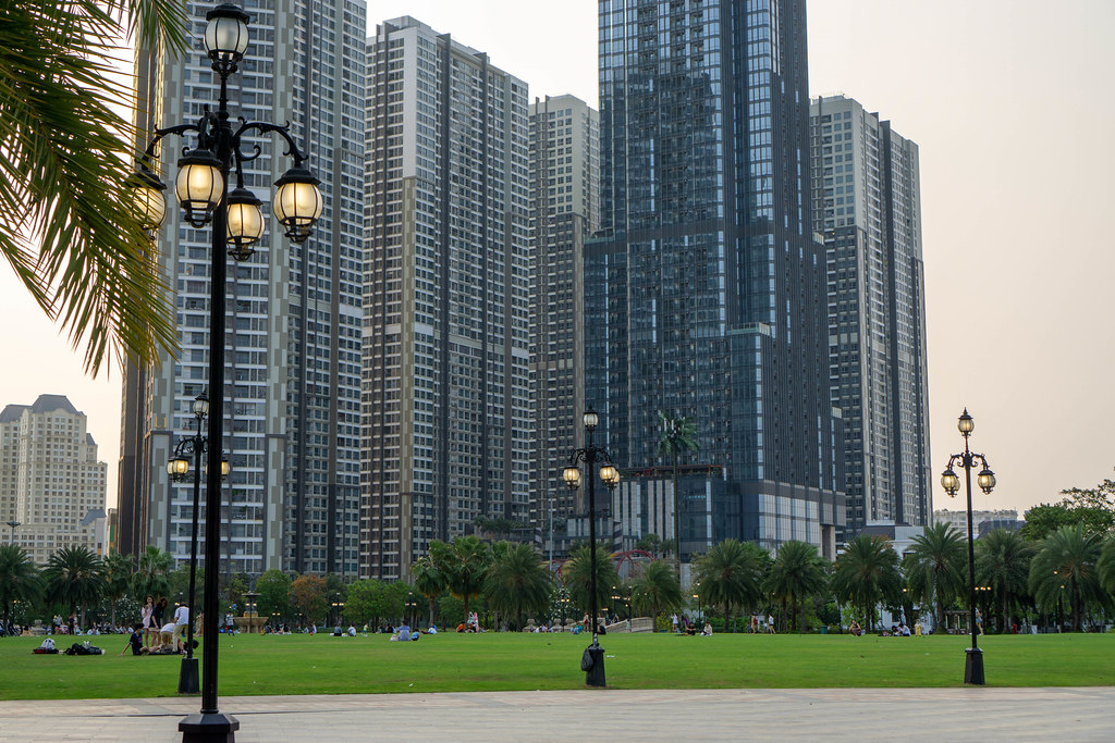 People on Large Lawn of Vinhomes Central Park with Vinhomes Apartment Buildings and Vincom Landmark 81 Building at Sunset in Ho Chi Minh City, Vietnam