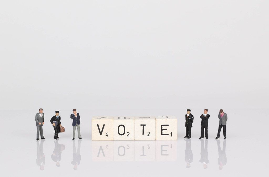 People standing next to vote text