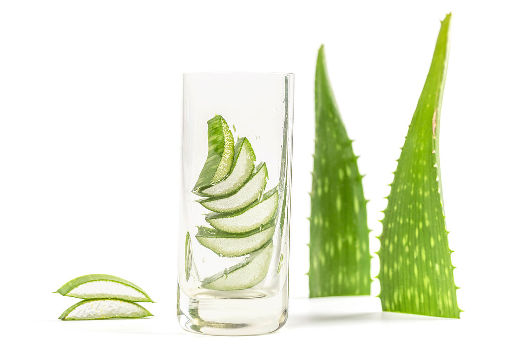 Pieces of fresh aloe vera in a glass and on a white background