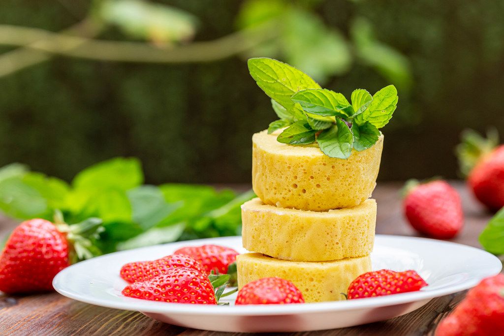 Pieces of sweet roll with fresh strawberries and mint on a blurred background of nature