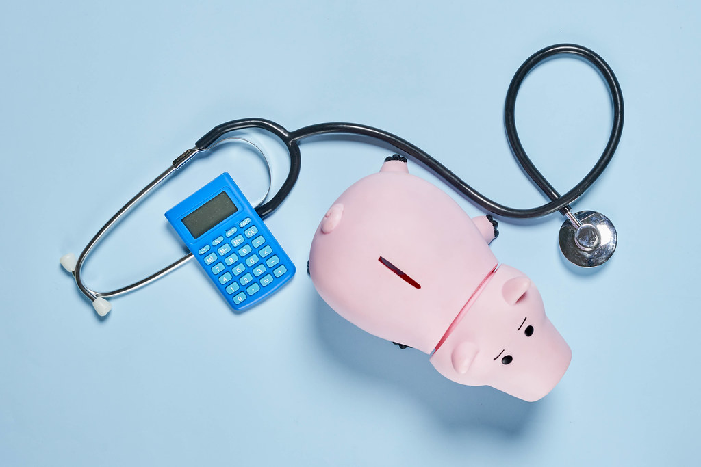 Piggy bank with stethoscope and calculator on blue background