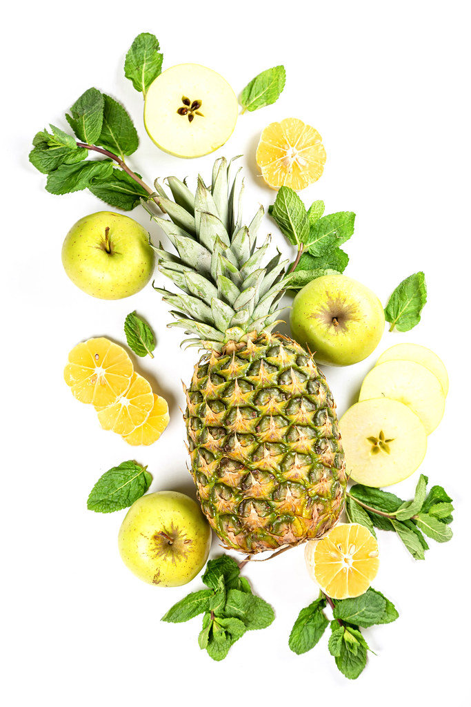 Pineapple with mint leaves, sliced apples and lemon, top view