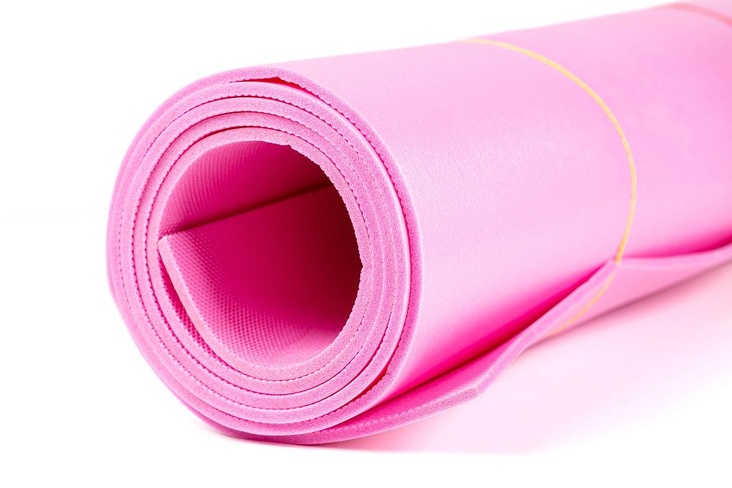 Pink yoga mat for exercise on white background