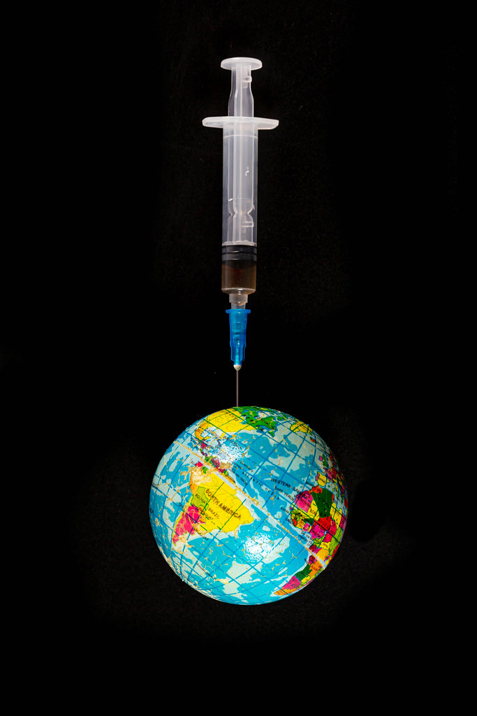 Planet earth on a needle of a medical syringe on a black background