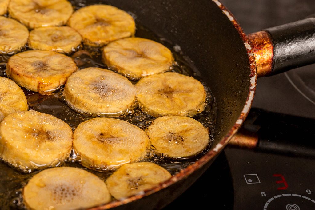 Plantain pieces are fried in a frying pan with oil