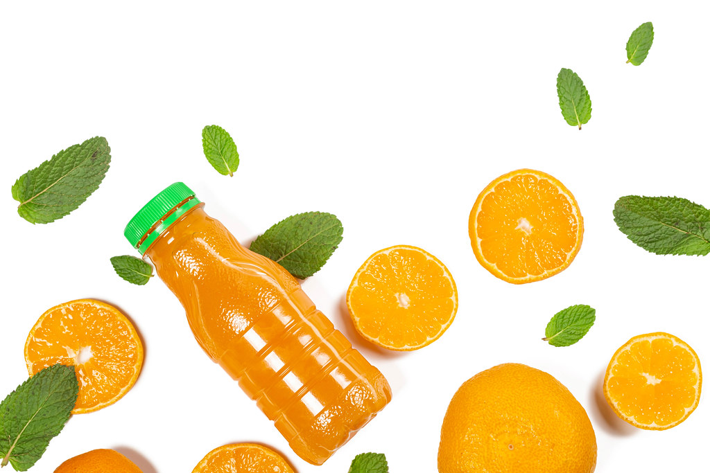 Plastic bottle with tangerine juice on white with tangerines and mint