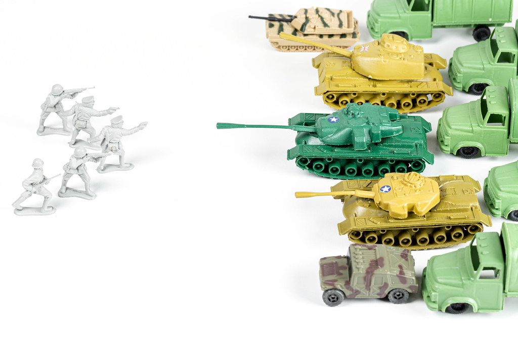 Plastic soldiers and tanks on a white background. Concept of combat operations