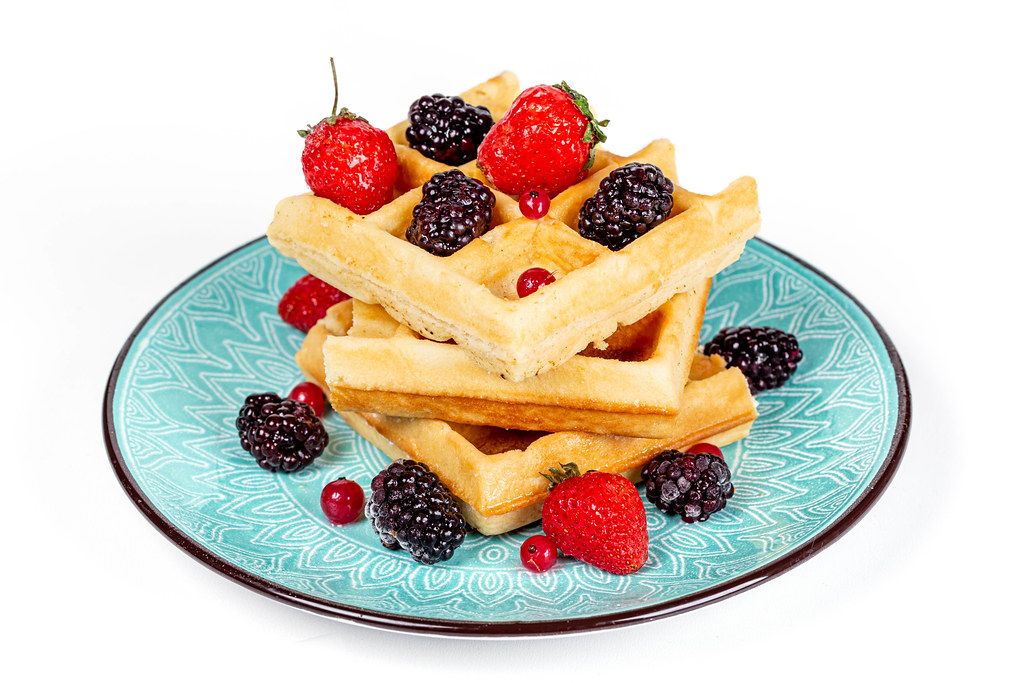 Plate of Belgian waffles with berries on a white background