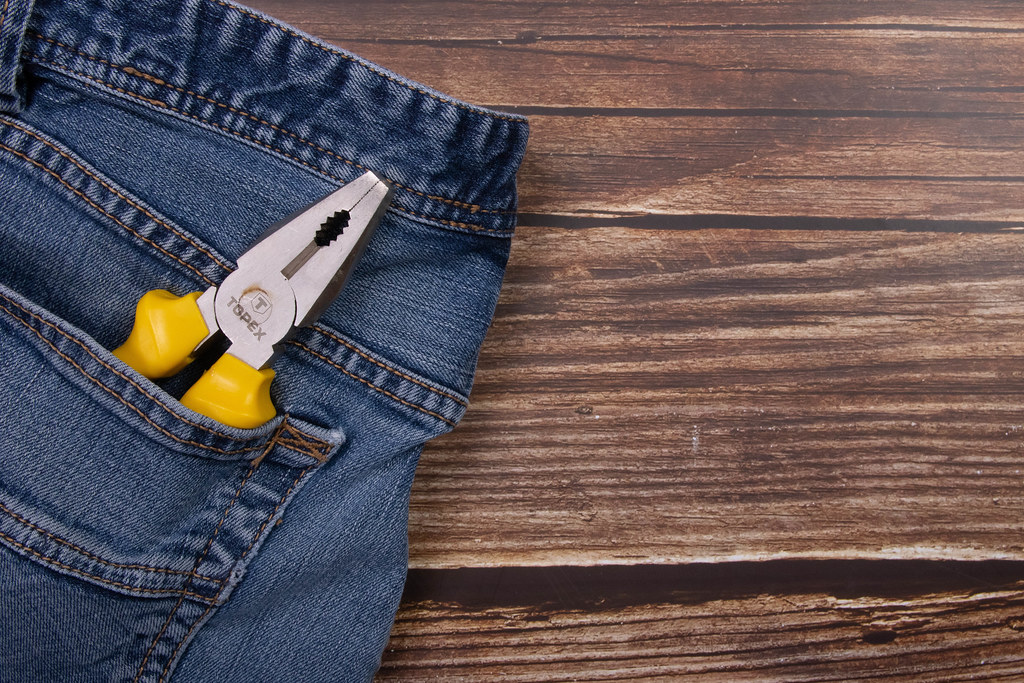 Pliers with yellow handle in a pocket of jeans