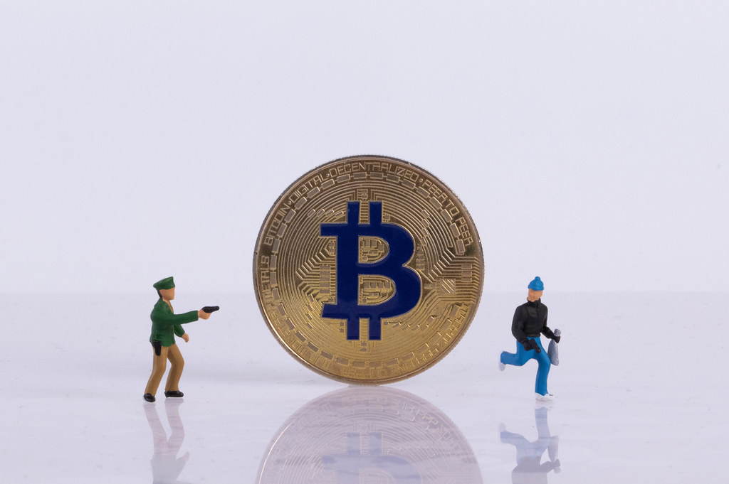 Policeman and robber with golden Bitcoin on white background