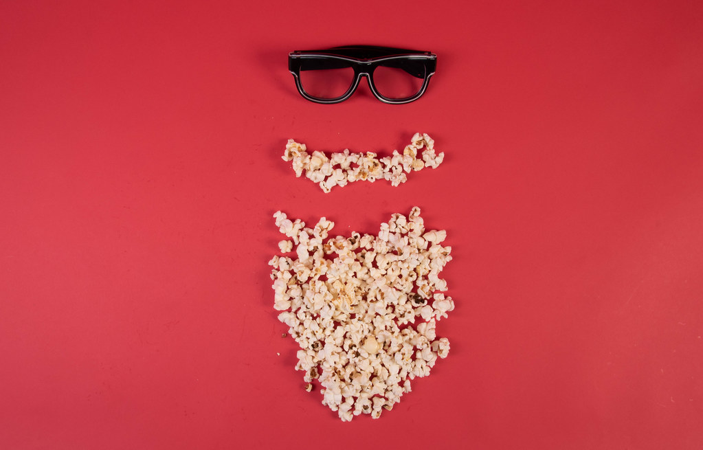 Popcorn and glasses on red background