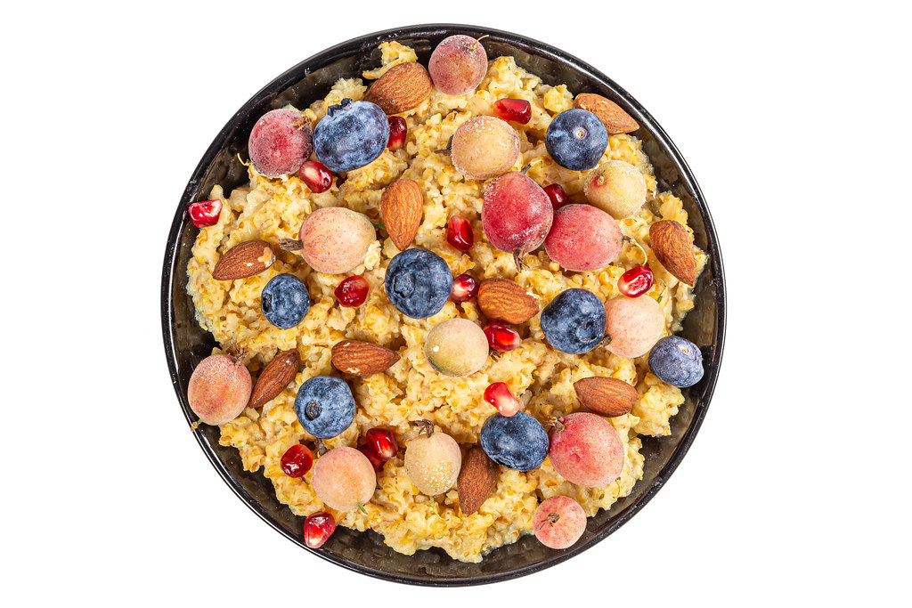 Porridge with gooseberries, blueberries, pomegranates and almonds, top view