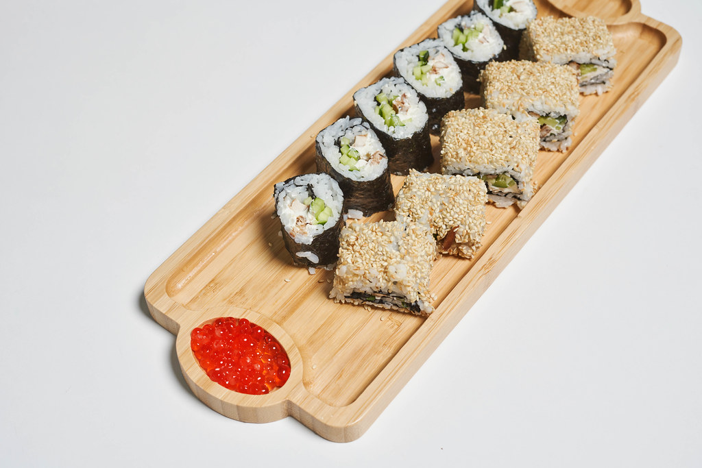 Portion of sushi served on wooden plate with red caviar