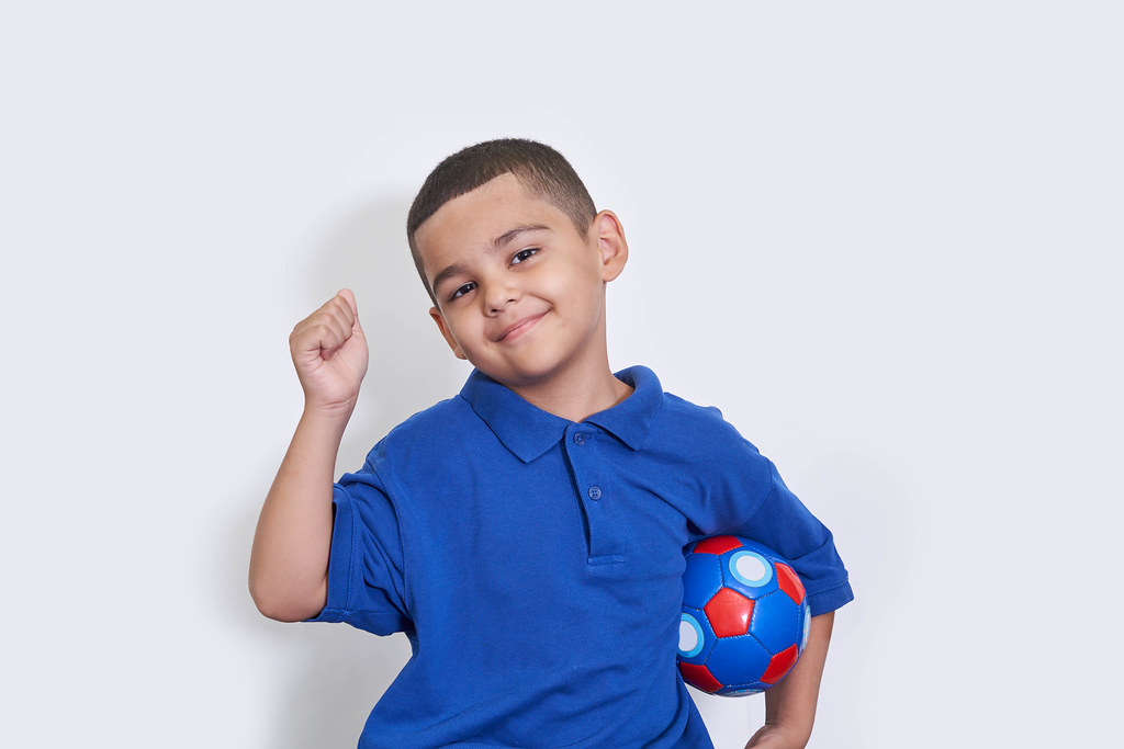 Portrait of happy kid boy with soccer ball celebrating championship win