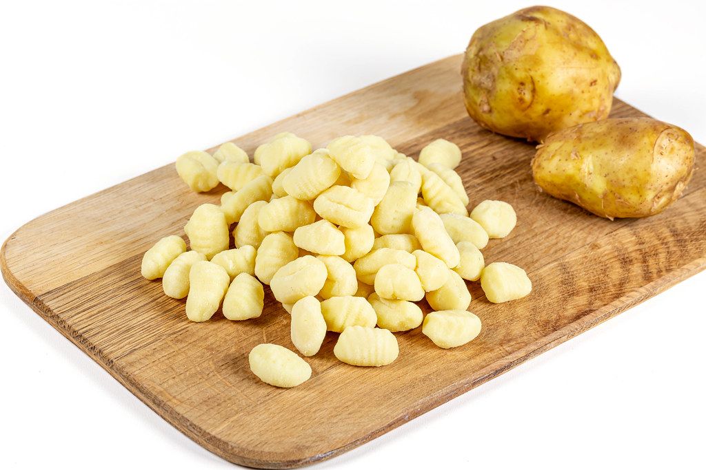 Potato gnocchi and young potato on kitchen board