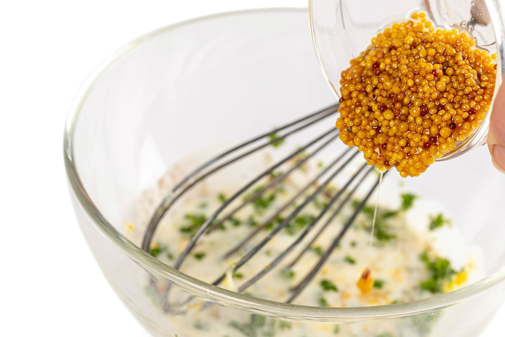 Pour mustard seeds into the marinade for meat, close-up