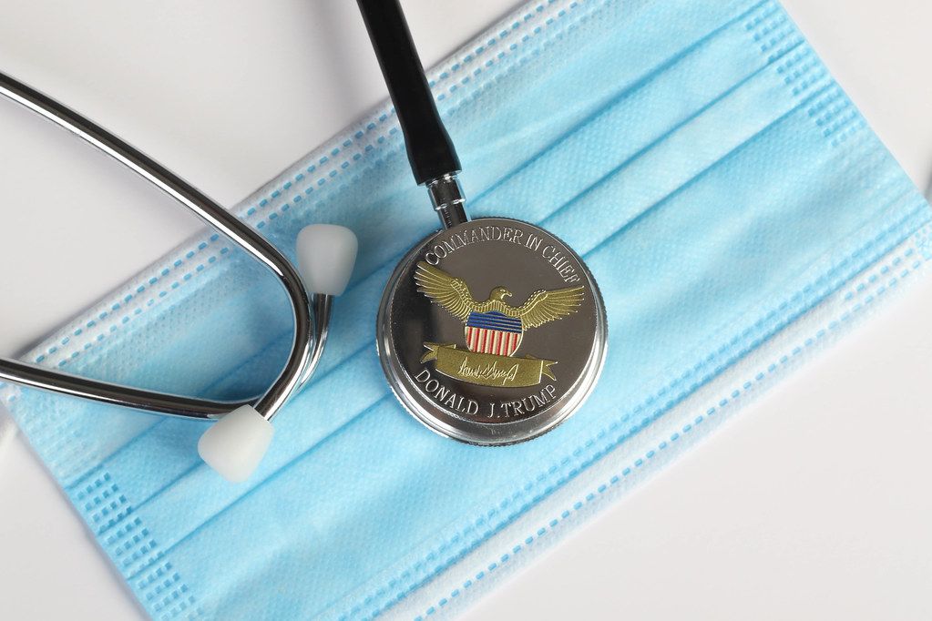 President Donald Trump coin and stethoscope on medical face mask