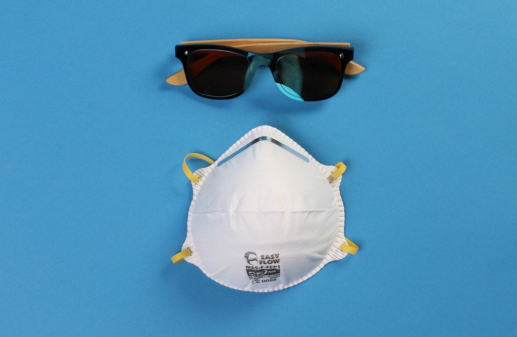 Protective mask and sunglasses on blue background