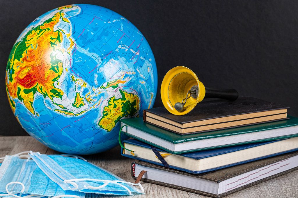 Quarantine restrictions in schools around the world concept. Globe, books and masks