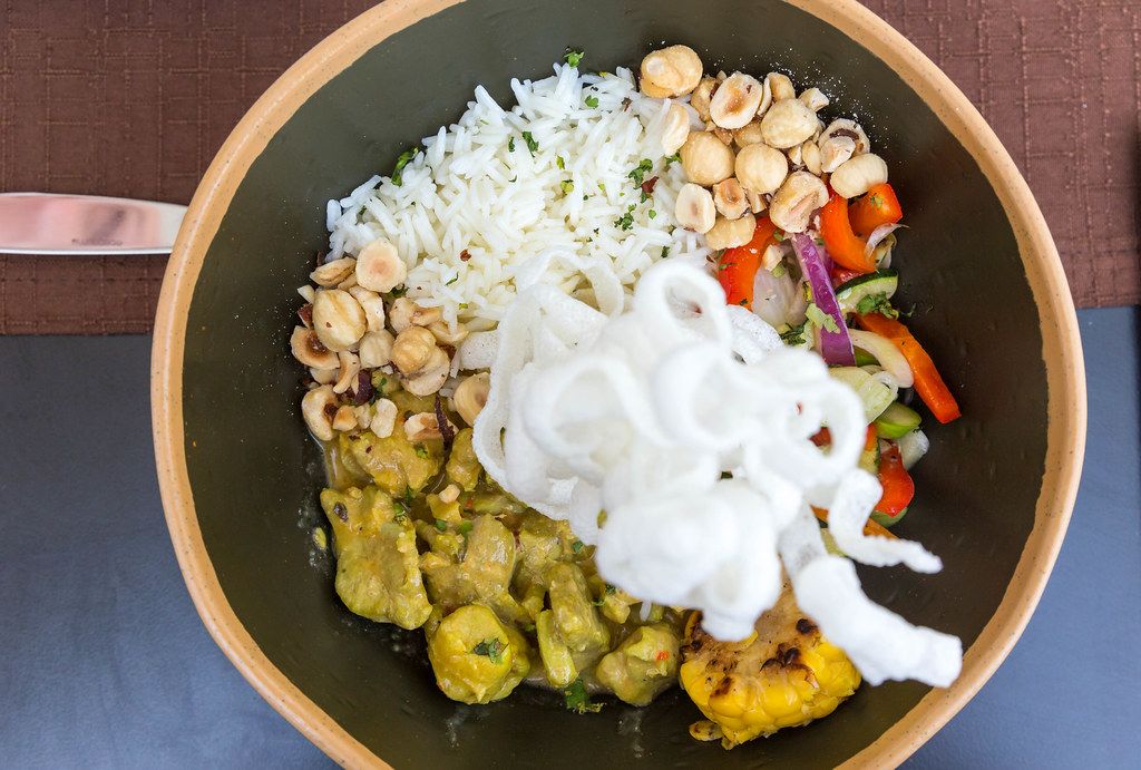 Range chicken in green curry sauce with seasonal veggies and rice. Top view in a bowl at Q11, Pollença