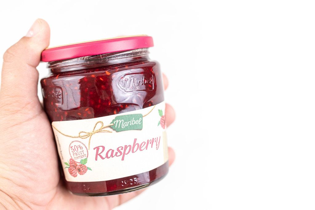 Raspberry Jam in the jar with copy space above white background