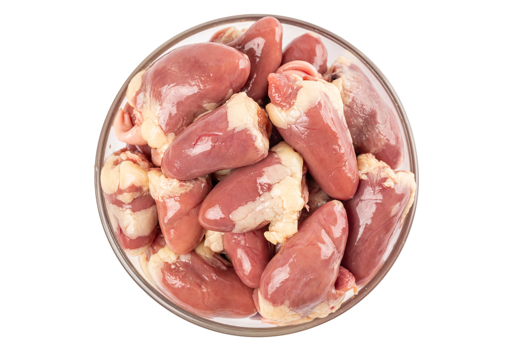 Raw chicken hearts in glass bowl, top view