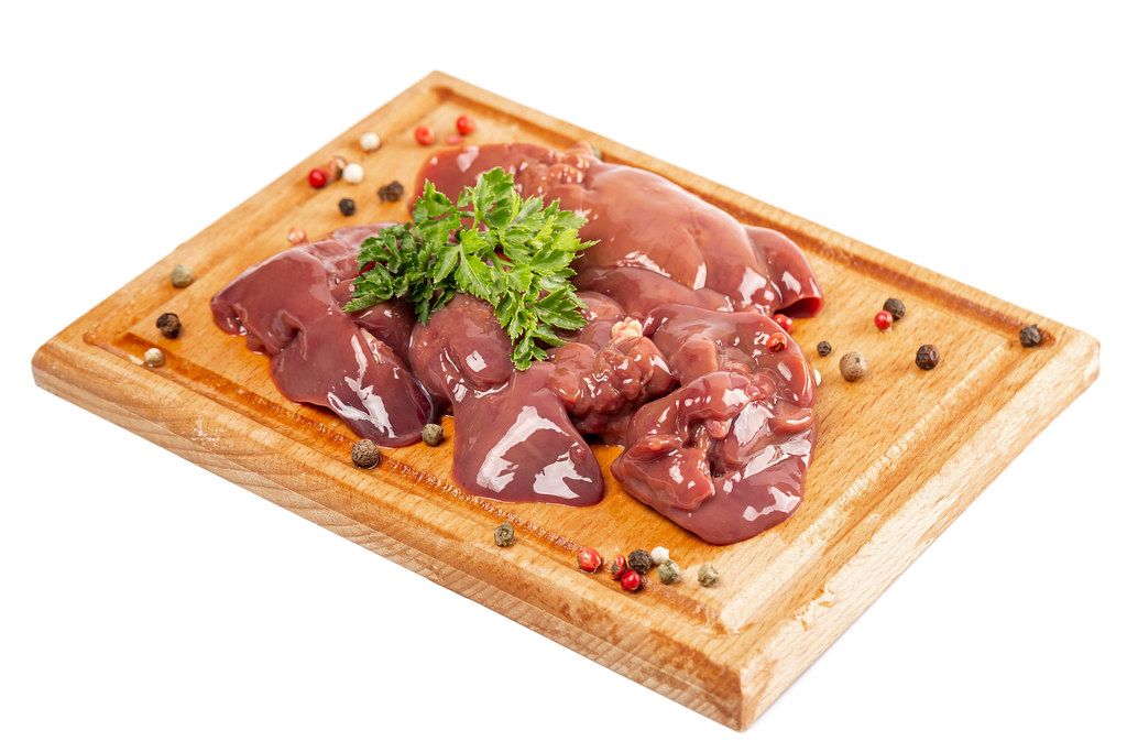 Raw chicken liver with spices on the kitchen board