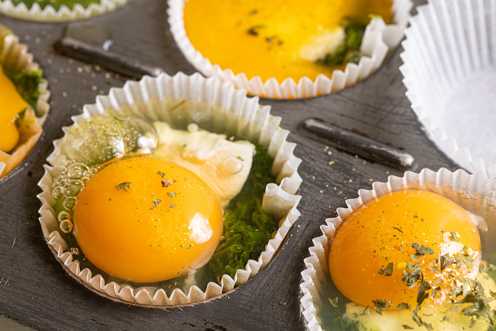 Raw Egg with cooked spinach in the cup cake tray ready for baking