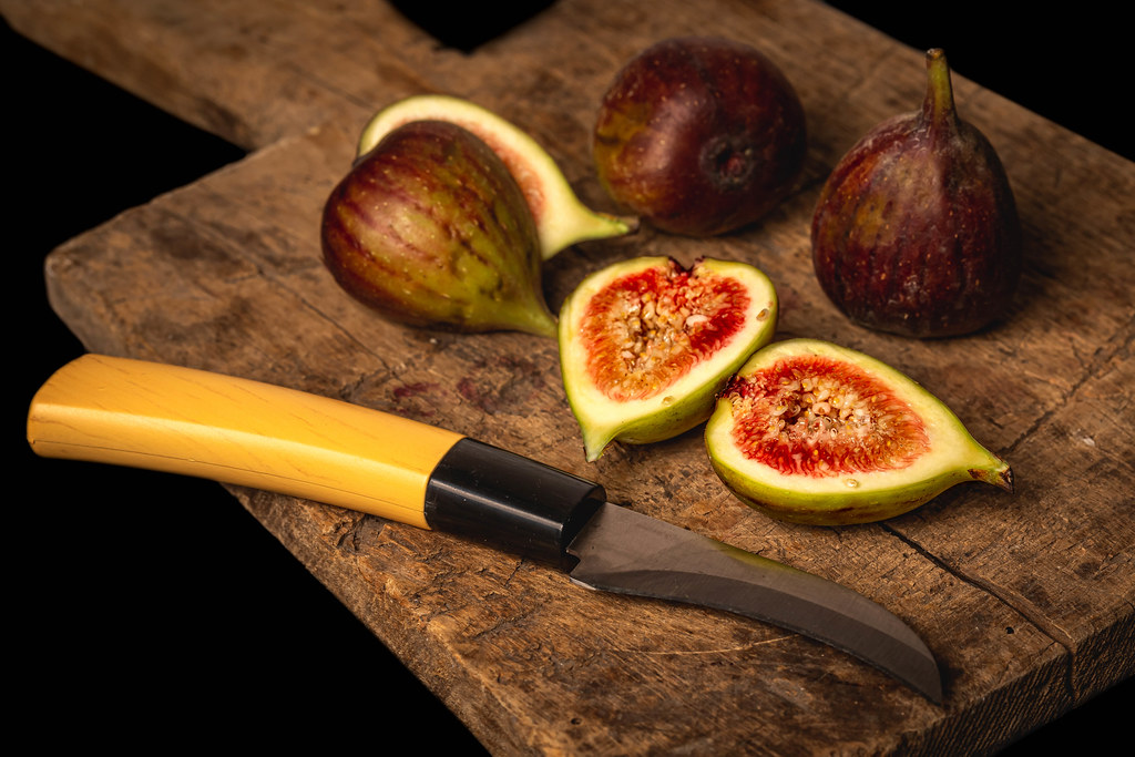 Raw fresh figs on vintage wooden board with knife