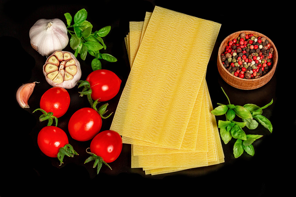 Raw ingredients for lasagna on a black background