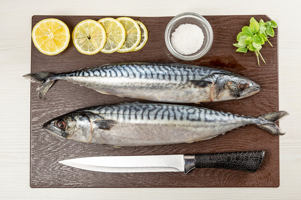 Raw mackerel on brown cutting board