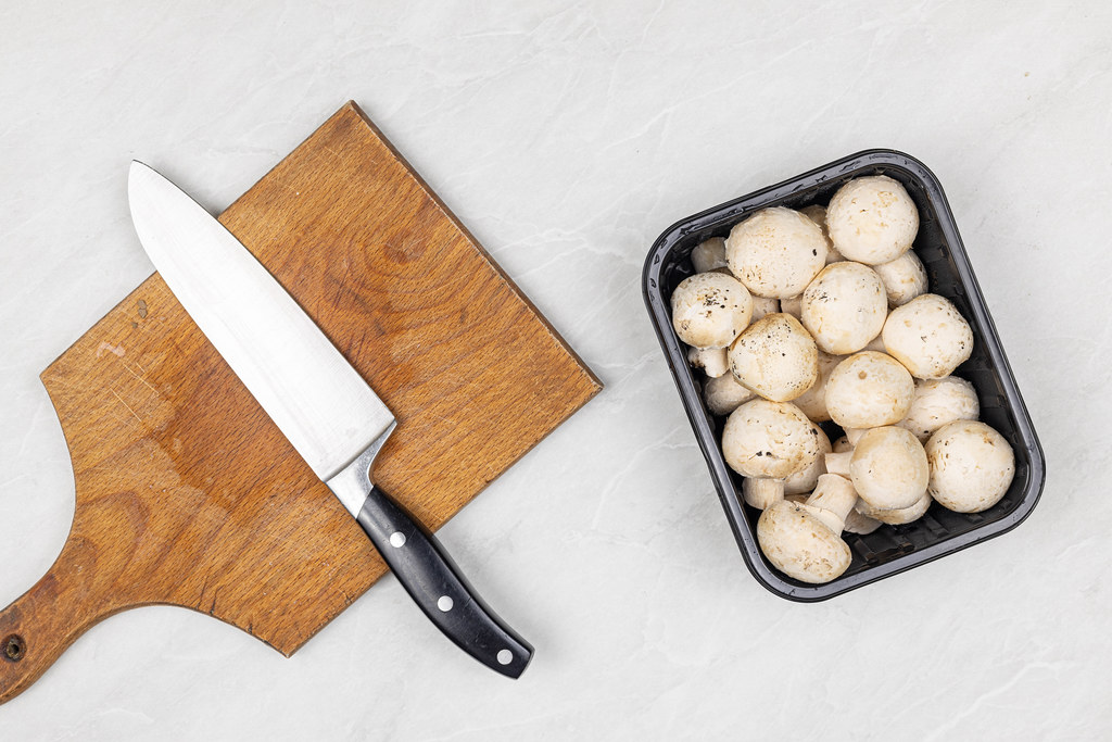 Raw Mushrooms on the table with cutting board and knife