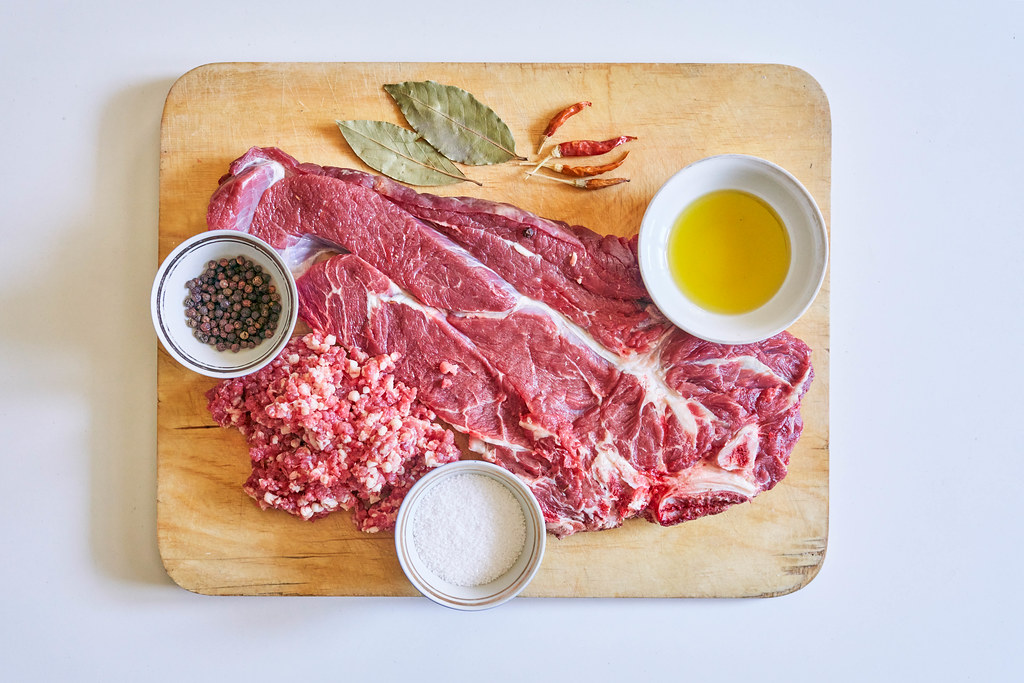 Raw rib-eye steak of beef with herbs and spices on cutting board