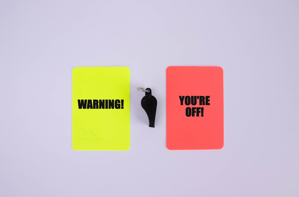Red and yellow referee cards with Warning and you're off text