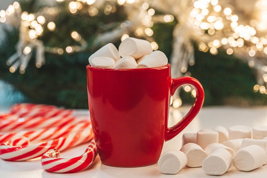 Red mug of cocoa with marshmallows on christmas background