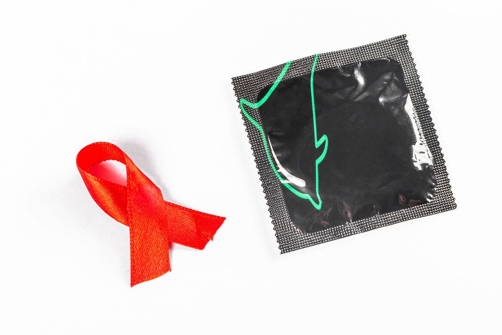 Red ribbon with a condom on white