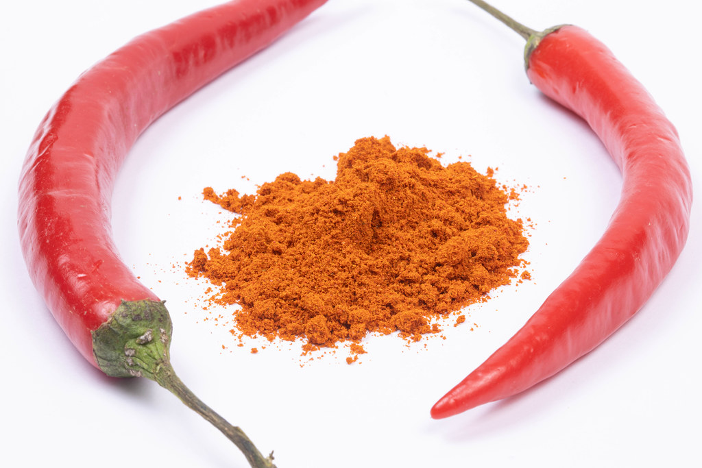 Red spicy Paprika powder with fresh paprika on the white background