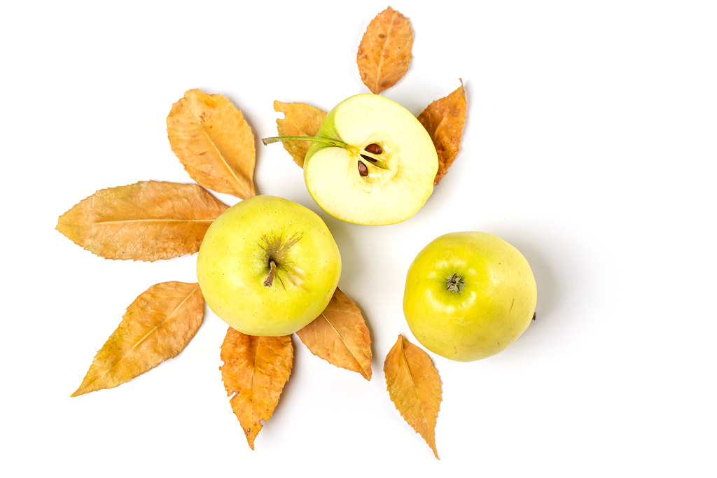 Ripe apples with dry yellow leaves on white