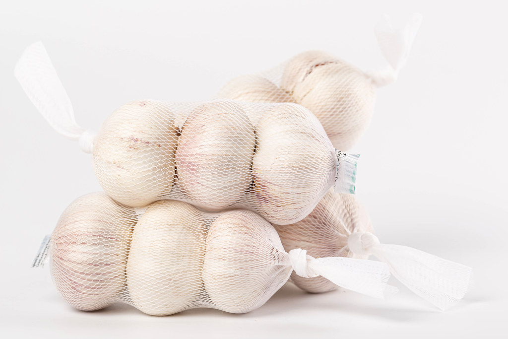 Ripe garlic in nets on a white background