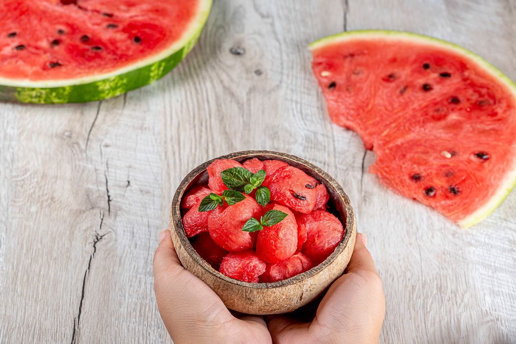 Ripe juicy watermelon pieces on a wooden background and in a bowl