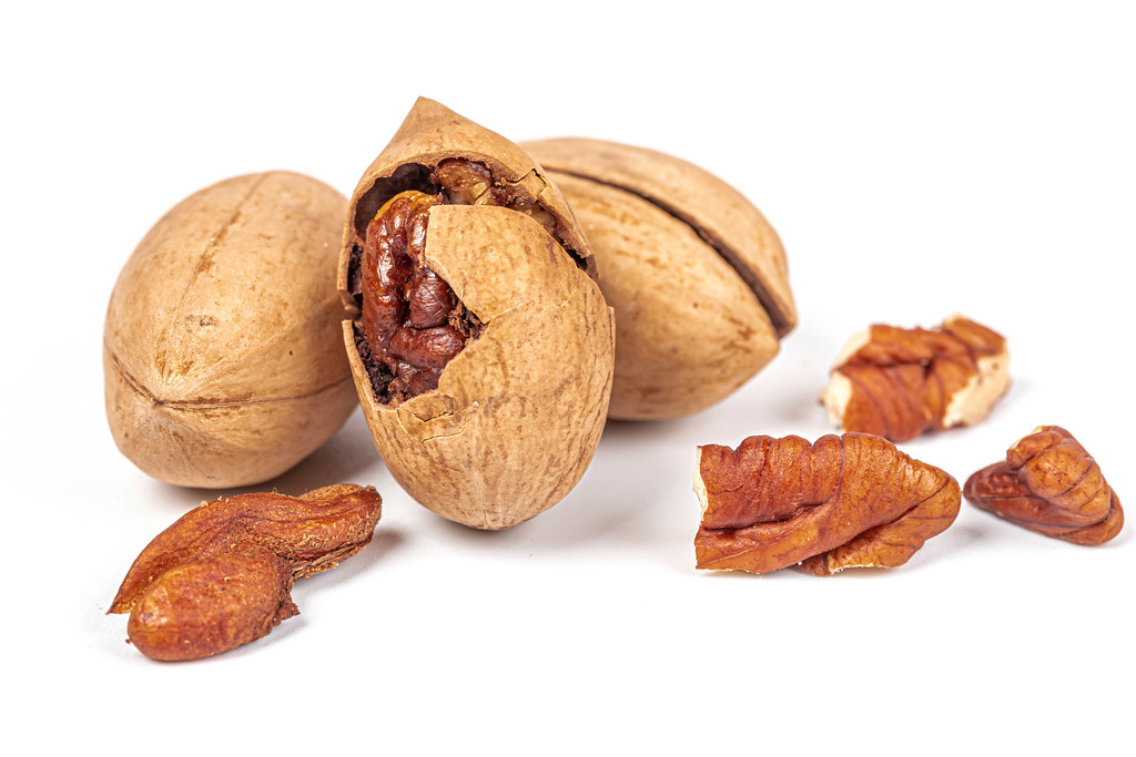 Ripe pecans with shells on a white background