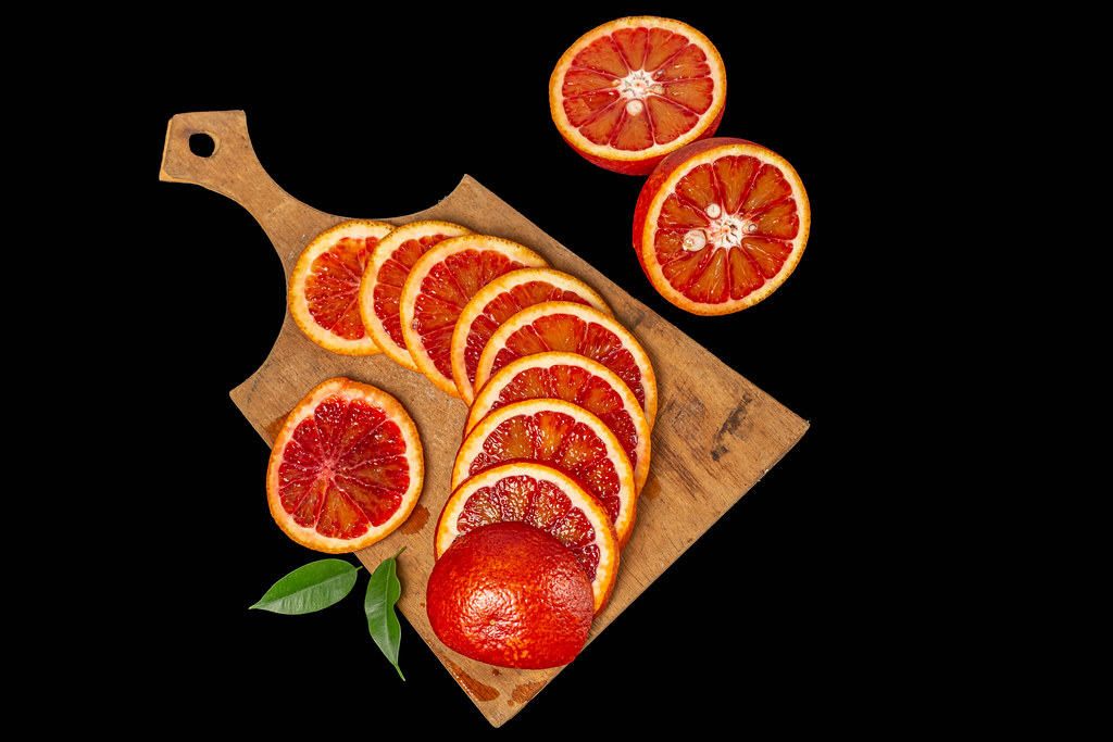 Ripe red oranges on dark background, top view