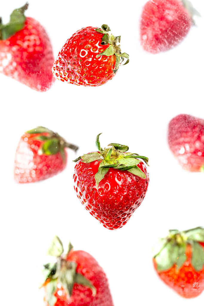 Ripe red strawberries falls, white background