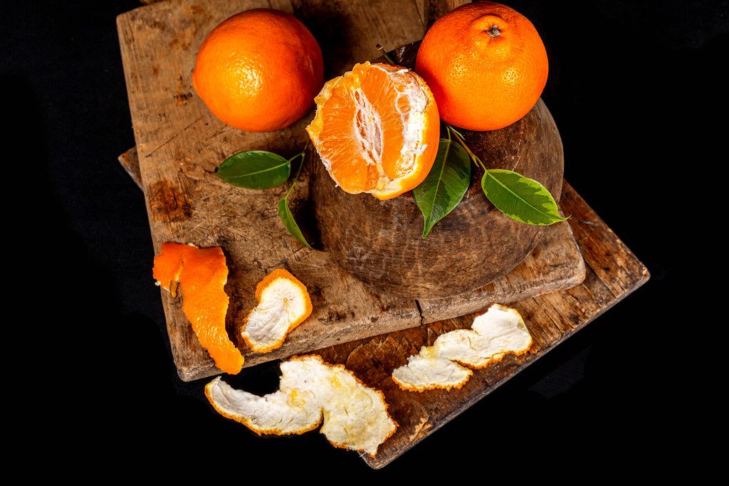 Ripe tangerines with leaves on a dark background, top view