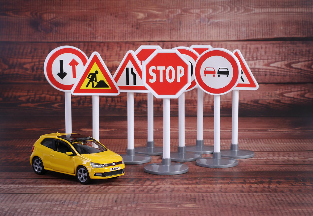 Road signs with yellow car on wooden table