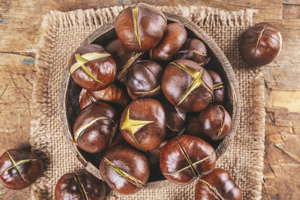 Roasted chestnuts on an old wooden background, top view