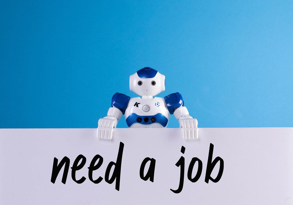 Robot holding a sign with Need a job text