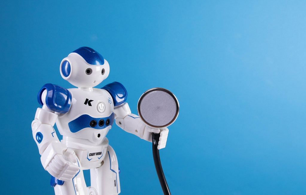 Robot holding stethoscope on blue background